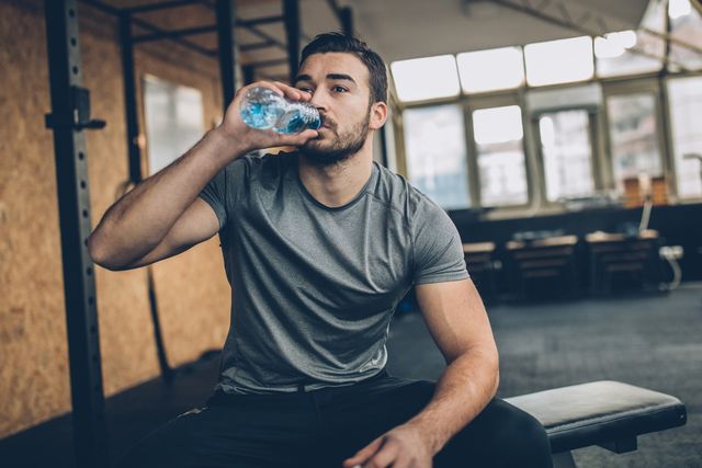 man drinking water after training in gym