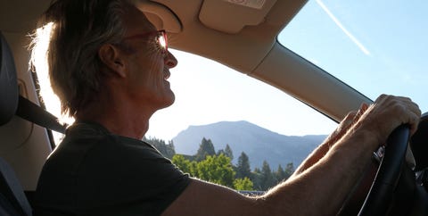 Man drives car along mountain road, sunrise