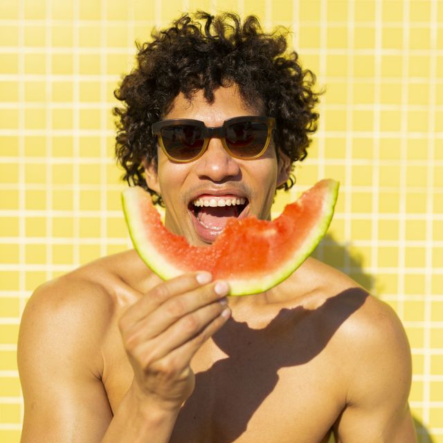 man eating a watermelon against a yellow background