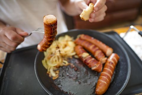 Man eating Sausages, close-up for breakfast on hot Electric Hob