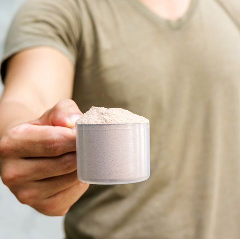 Man holding a whey protein on gray background.