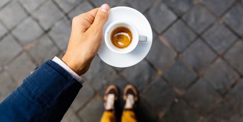 Man holding cup of espresso coffee, personal perspective view