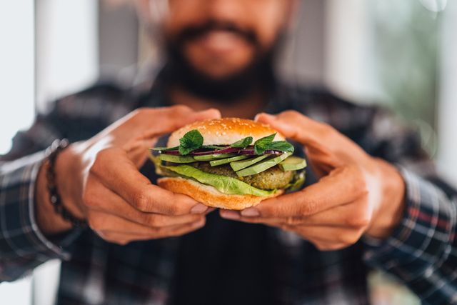 man holding vegan chickpea burger in hand