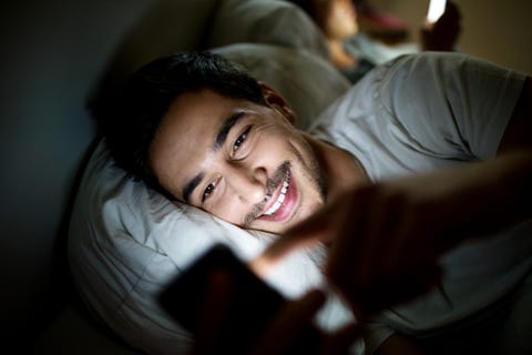 uomo a letto che controlla il suo stato sui social media sullo smartphone