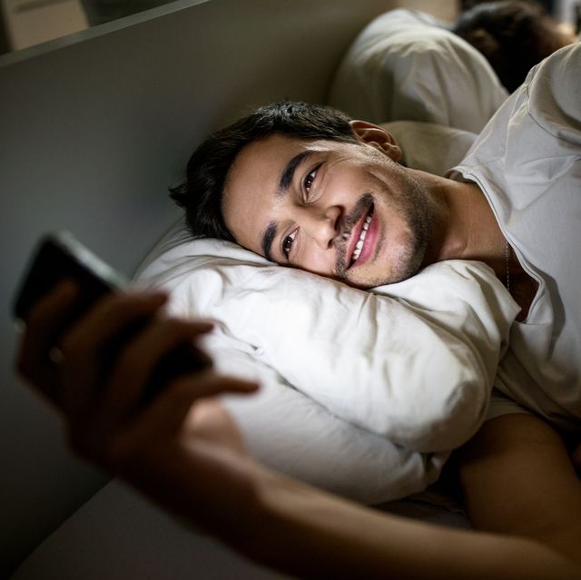 man in bed using mobile phone