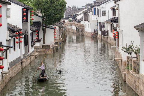 a man is training fish hawk on canal in ancient luzhi town