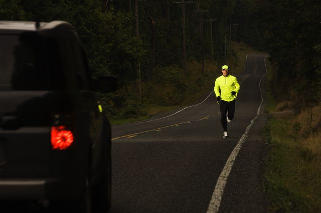 man jogging on road, car approaching, dusk