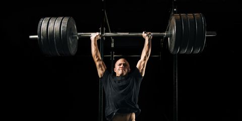 Man lifting heavy barbell in gymnasium