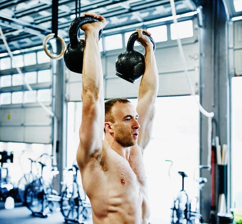 Man lifting kettlebell above his head during exercise Man lifting kettlebell above his head during exercise