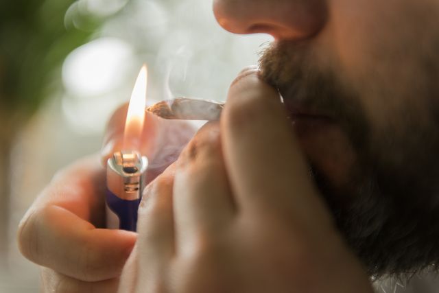 man lighting marijuana joint