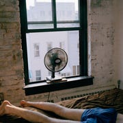 A man lying on a bed with a fan blowing a man lying on a bed with a fan blowing