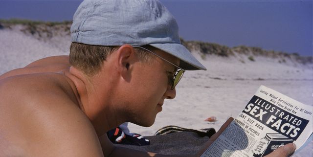 man lying on beach reading magazine, close up
