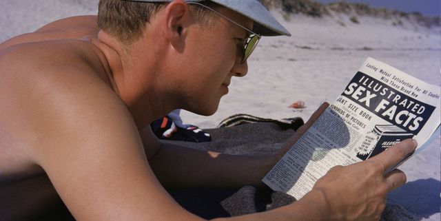man lying on beach reading magazine, close up
