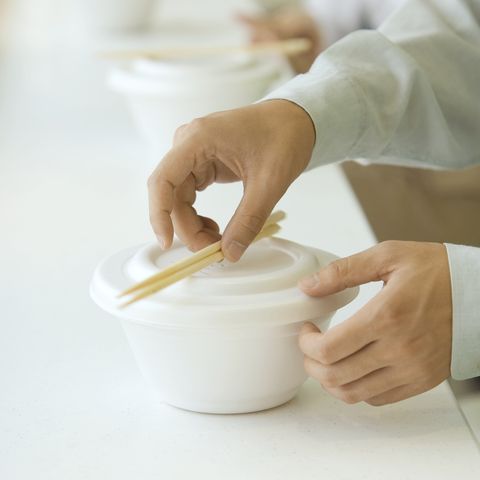 man picking up chopsticks on take out food container, cropped view