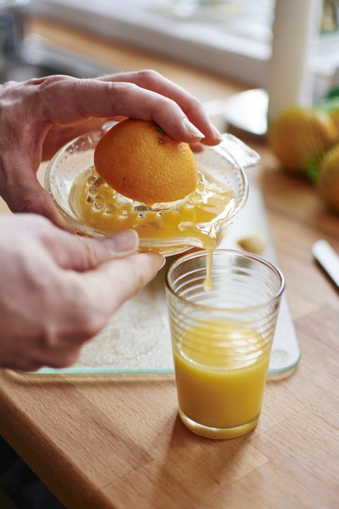 man pouring freshly squeezed orange juice into a jar