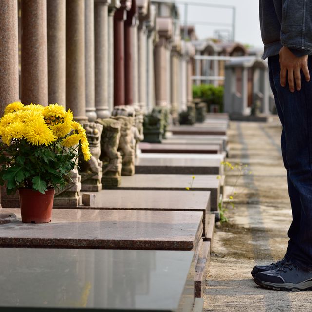 man put flower in front of tomb of ancestor