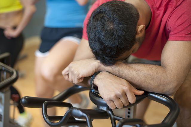 man resting on spin machine in gym