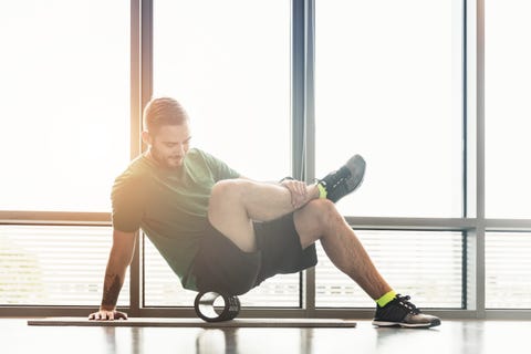 El hombre rueda sus muscules delante de una ventana