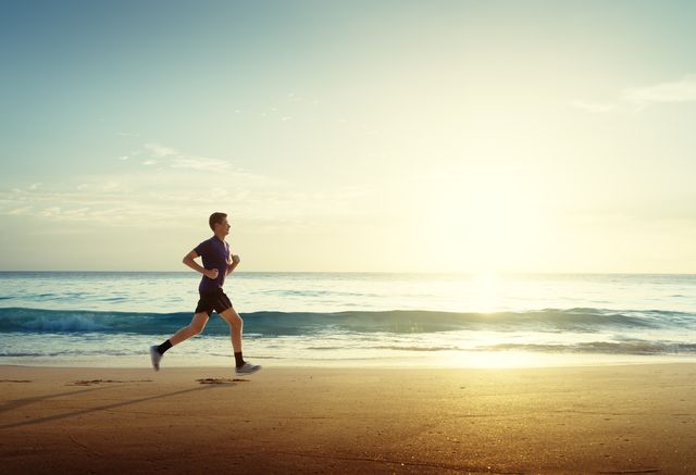 man running on tropical beach at sunset