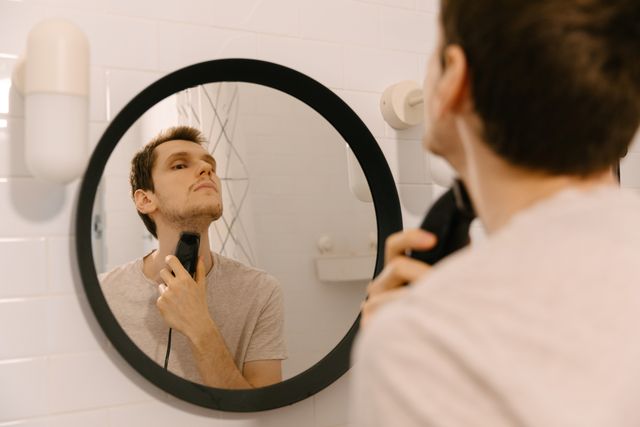 man shaving in front of the mirror in bathroom