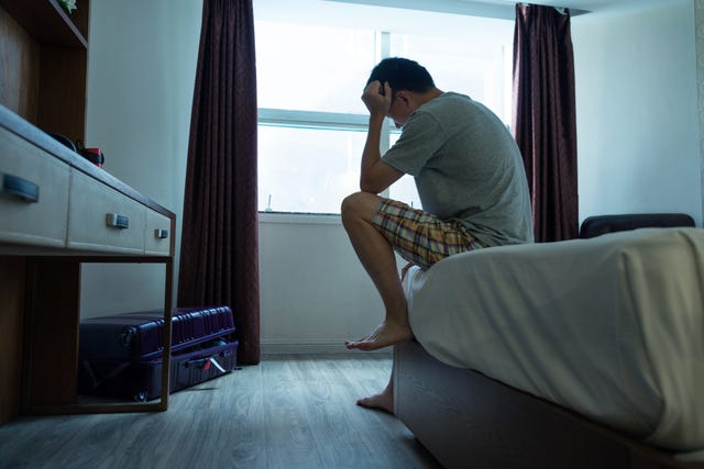 man sitting on bed with head in hands