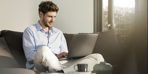 Man sitting on couch at home using laptop