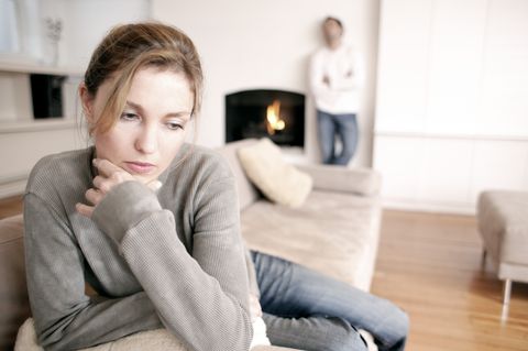 man sitting on sofa while woman standing in background