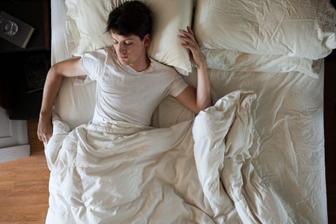 man sleeping alone in double bed