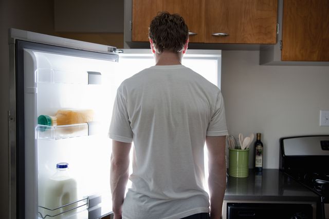 man standing looking at contents of fridge