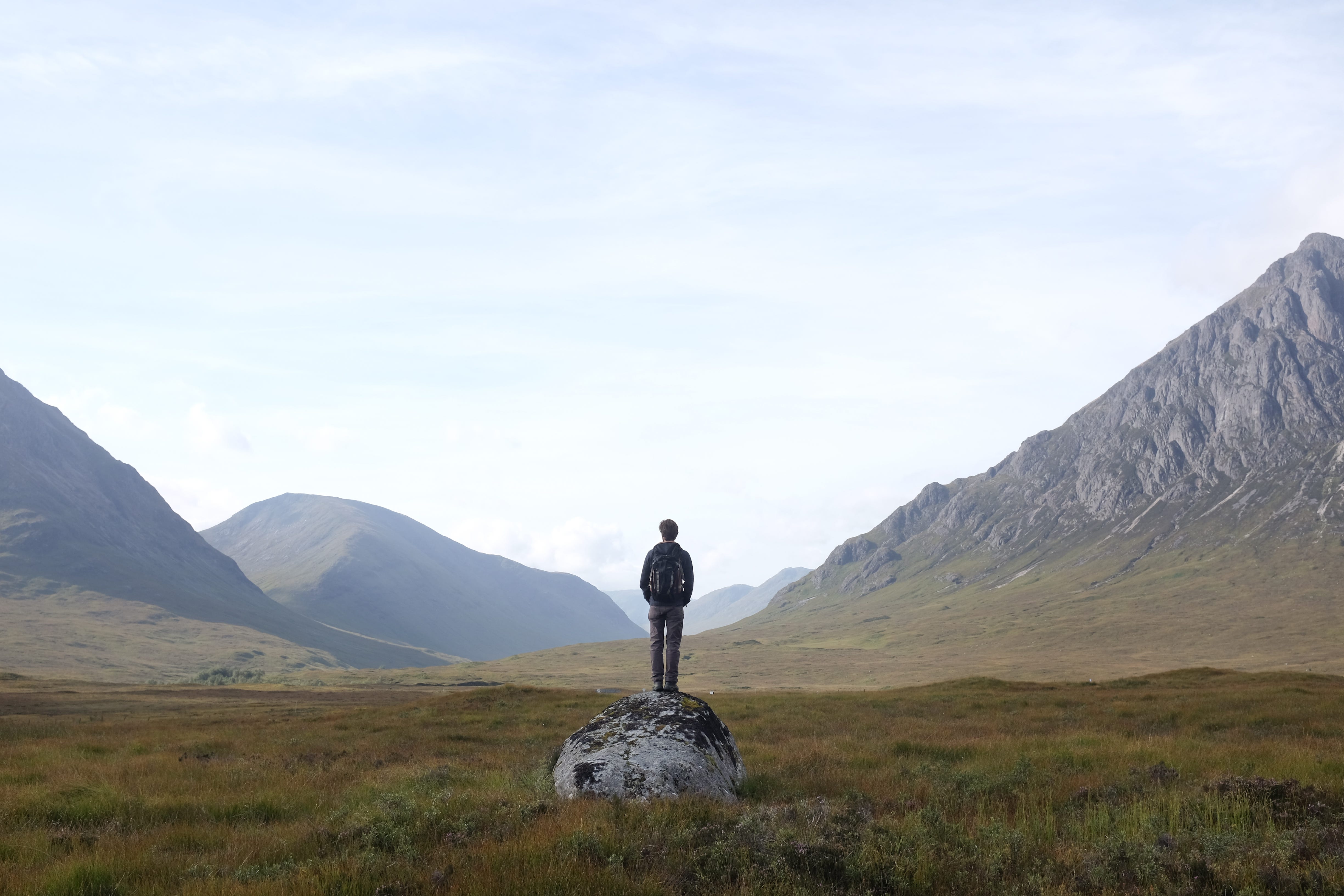 Hombre de pie sobre una roca mirando la vista, Highlands, Escocia, Reino Unido