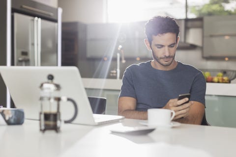 Man texting with cell phone at kitchen table