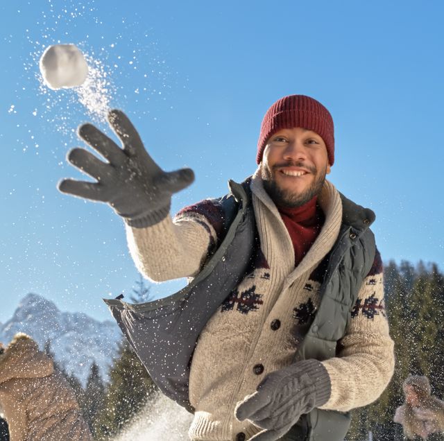 hombre tirando nieve con gorro de lana