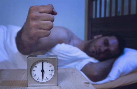 Man turning off alarm clock with fist