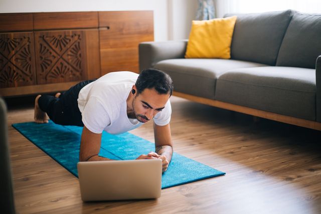 man uses laptop to lean plank position