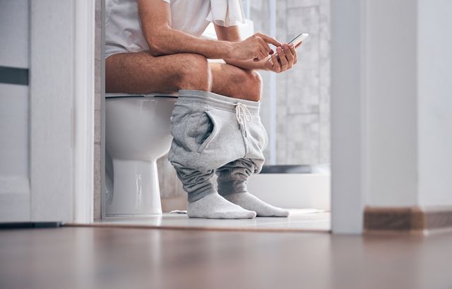 man using his gadget in the water closet