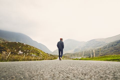 man walking down a country road in killarney, ireland