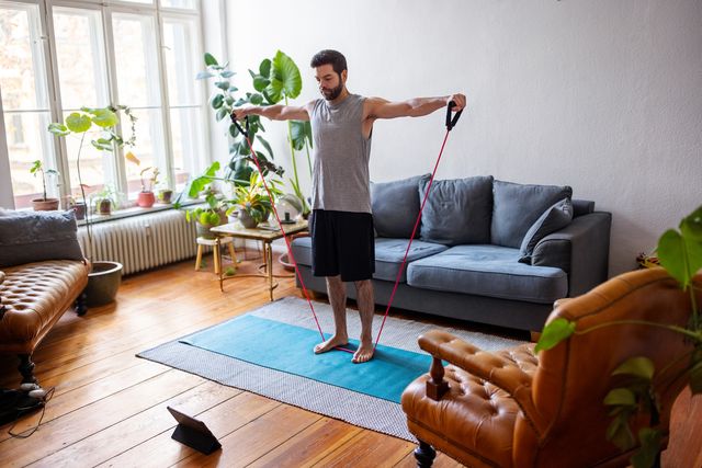 man watching online videos and doing exercise at home