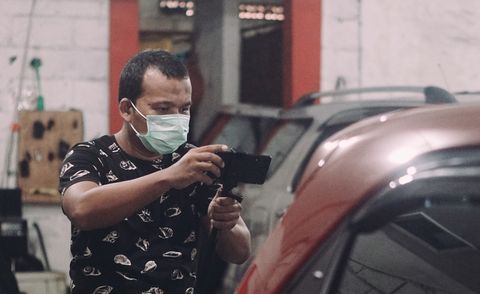 homme portant un masque photographiant une voiture