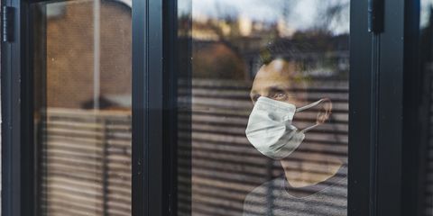 Man with mask looking out of window