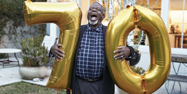 man with number 70 balloons laughing in backyard