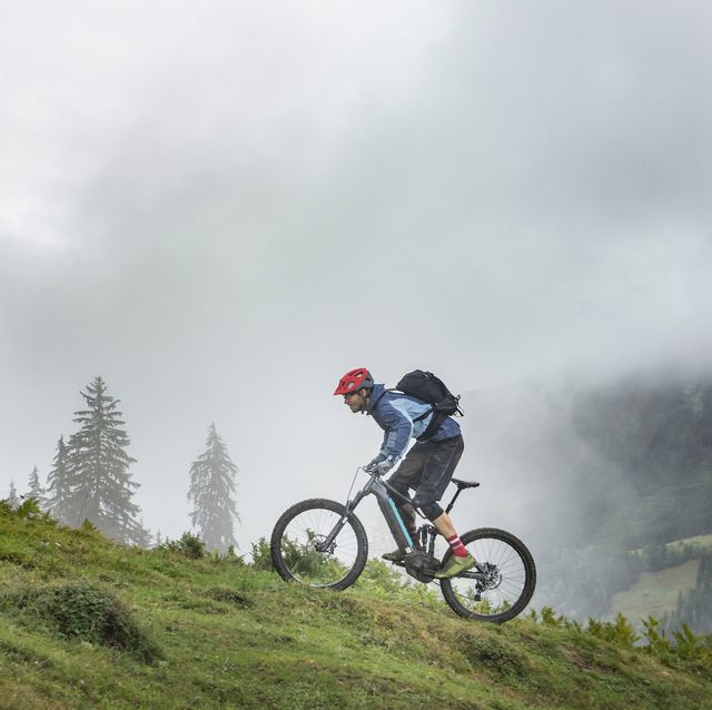 man with pedelec riding uphill in mountains, saalfelden, tyrol, austria