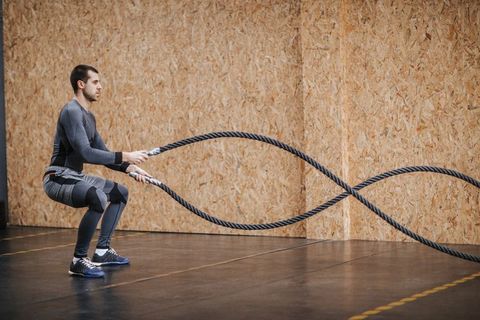 Man working out with battle ropes at a gym