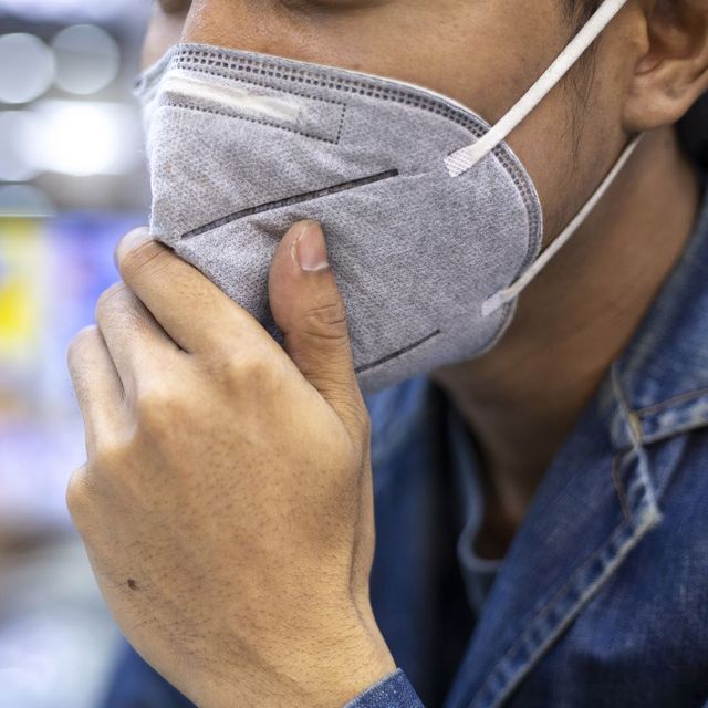 close up portrait of a man using pm 25 pollution mask in the street of a big city