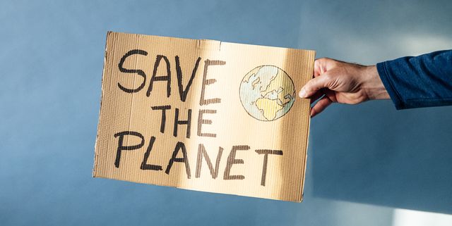 man's hand holding a cardboard sign that says save the planet