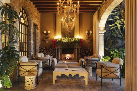 large rope chandeliers and a roaring fire illuminate a cozy sala abierta outdoor living room