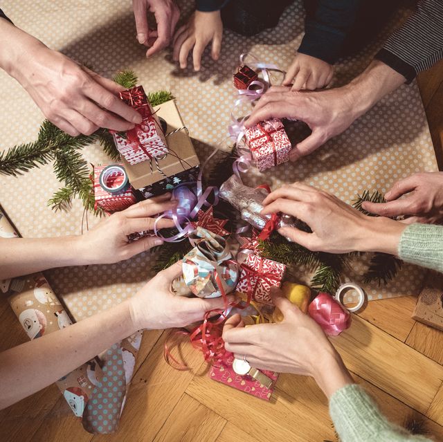 many hands taking christmas gifts from wooden floor for secret santa