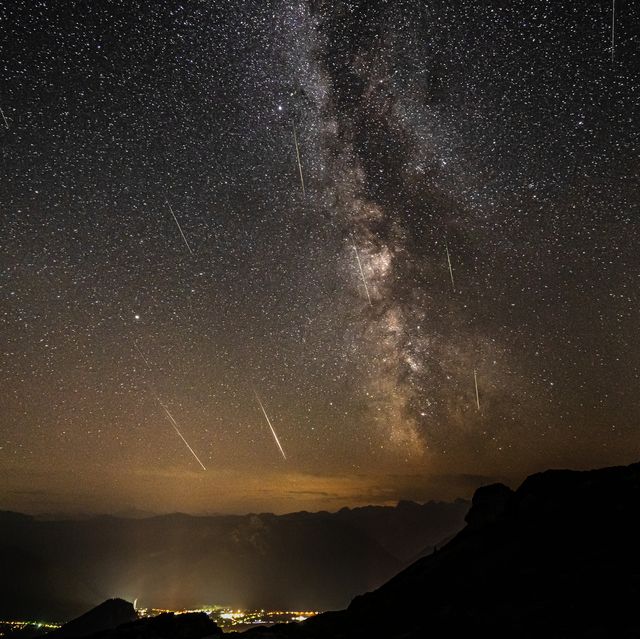 many stars, milky way and perseids on night sky in the mountains over valley