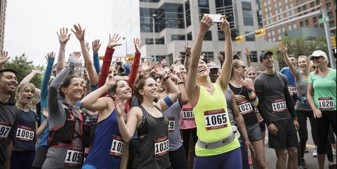 Marathon runners posing, waving and cheering for selfie at starting line on urban street