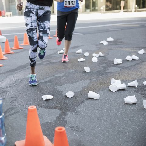 Marathon runners rounding corner with paper cups on street