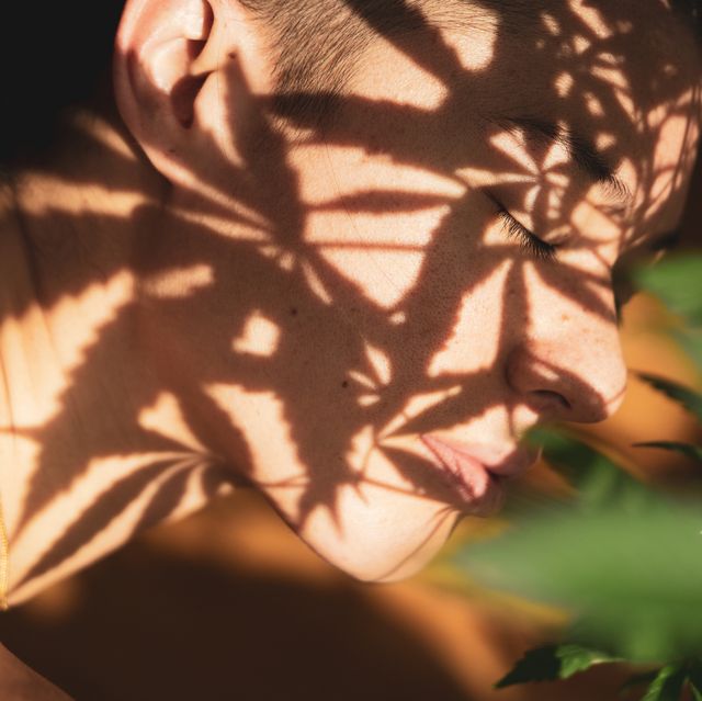 marijuana leaves cast shadow on peaceful face with eyes close